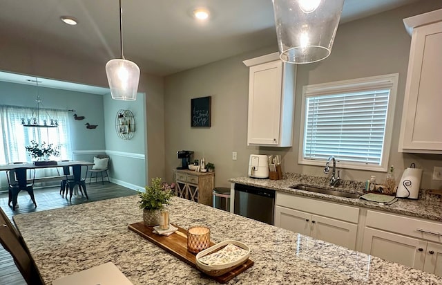 kitchen with a sink, light stone counters, dishwasher, and white cabinets