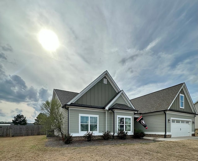 craftsman inspired home with fence, roof with shingles, an attached garage, a front lawn, and board and batten siding