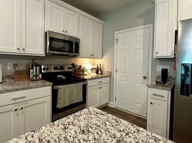 kitchen with light stone counters, white cabinetry, and stainless steel appliances