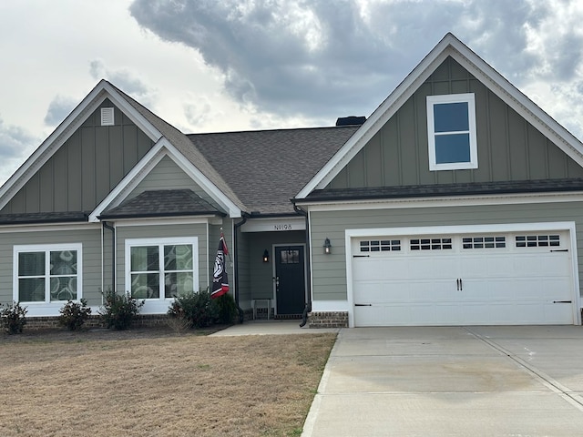 craftsman-style home featuring board and batten siding, concrete driveway, a front lawn, and a shingled roof