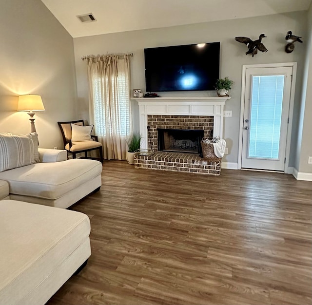 living room with wood finished floors, visible vents, baseboards, a fireplace, and vaulted ceiling