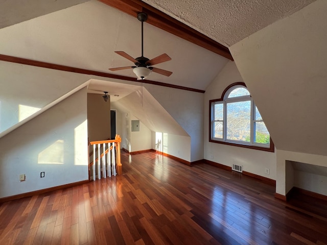 additional living space with dark wood-type flooring, ceiling fan, a textured ceiling, and vaulted ceiling with beams