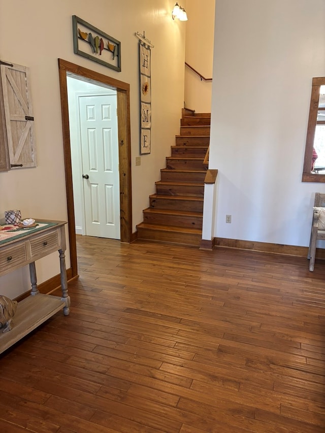 interior space with stairs, dark wood-style flooring, and baseboards