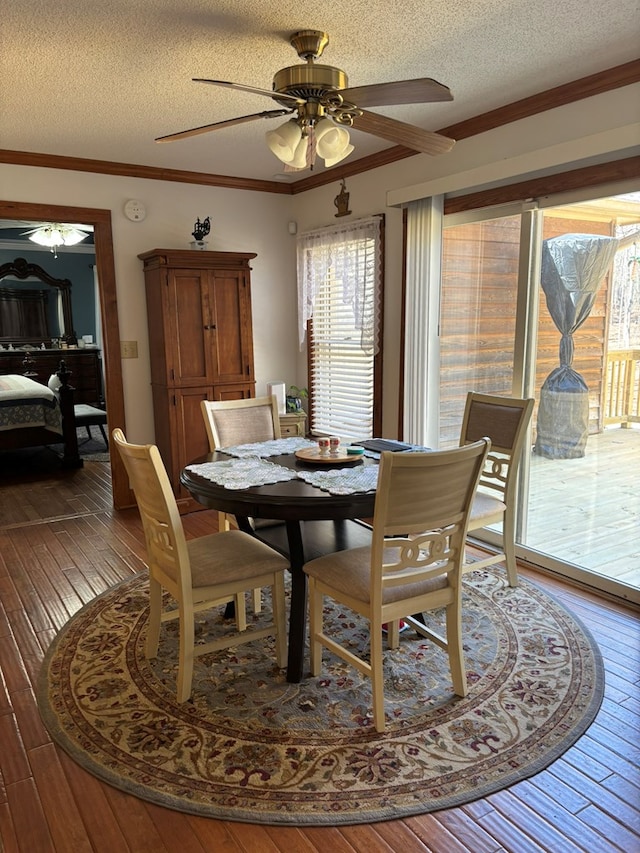 dining area with a ceiling fan, a textured ceiling, ornamental molding, and wood finished floors