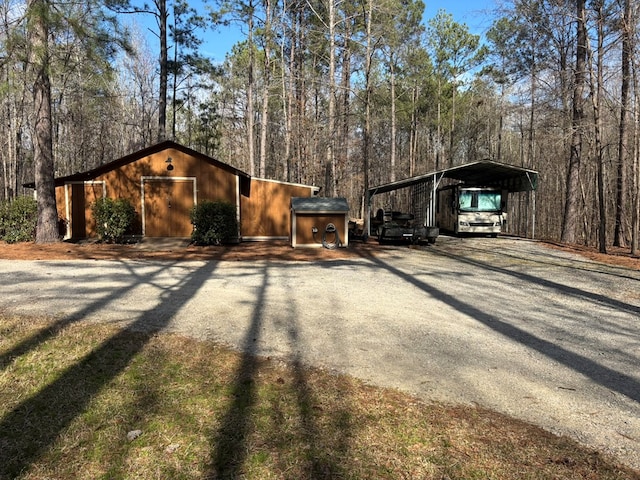 view of home's exterior featuring driveway, an outbuilding, and a detached carport