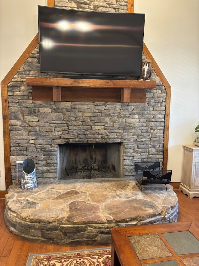 interior details with a stone fireplace and wood finished floors