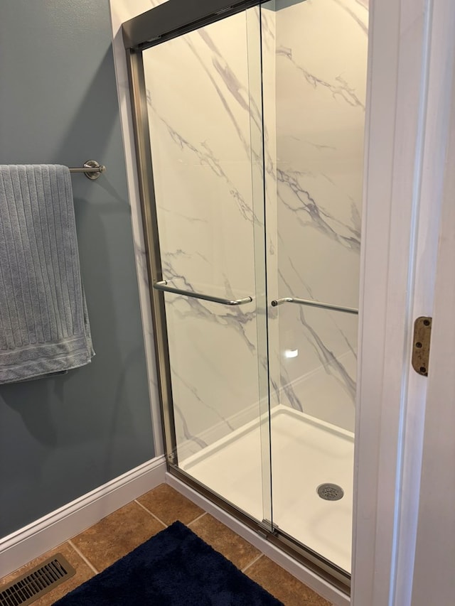 full bath with baseboards, a marble finish shower, visible vents, and tile patterned floors