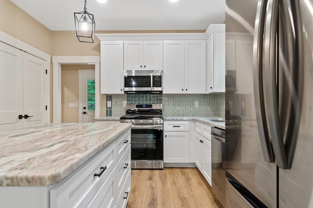 172 Southshore Rd, Eatonton, GA 31024 - kitchen with appliances with stainless steel finishes, decorative backsplash, white cabinets, light stone counters, and light wood-type flooring