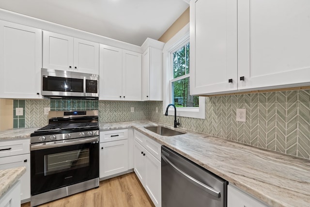 172 Southshore Rd, Eatonton, GA 31024 - kitchen featuring appliances with stainless steel finishes, white cabinets, light stone counters, decorative backsplash, and light wood-type flooring
