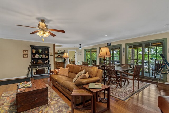 living room with plenty of natural light, hardwood / wood-style floors, crown molding, and a ceiling fan