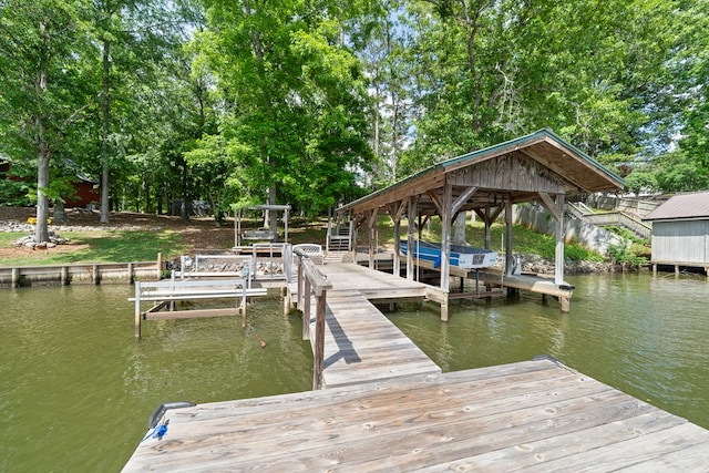 dock area featuring a water view, boat lift, and view of scattered trees