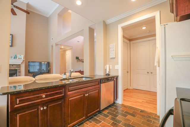 kitchen with dishwasher, sink, a stone fireplace, white refrigerator, and kitchen peninsula