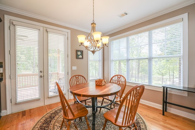 dining space featuring light hardwood / wood-style floors, french doors, ornamental molding, and a notable chandelier