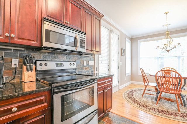 kitchen with a wealth of natural light, tasteful backsplash, a notable chandelier, dark stone counters, and appliances with stainless steel finishes