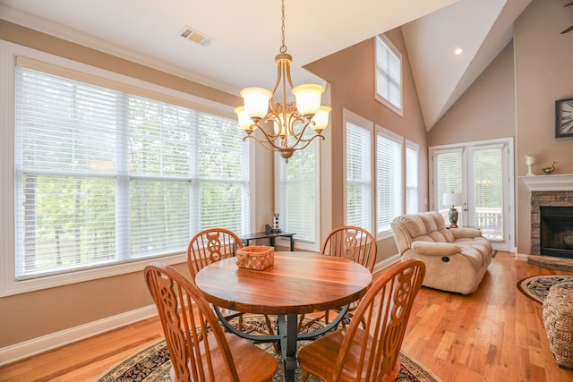 dining room featuring a notable chandelier, ornamental molding, a fireplace, and light hardwood / wood-style flooring