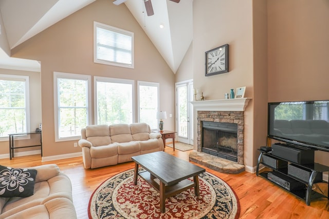 living room featuring ceiling fan, light hardwood / wood-style floors, a fireplace, and vaulted ceiling