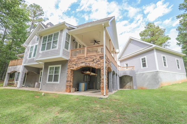 rear view of property with ceiling fan, a balcony, a yard, and a patio