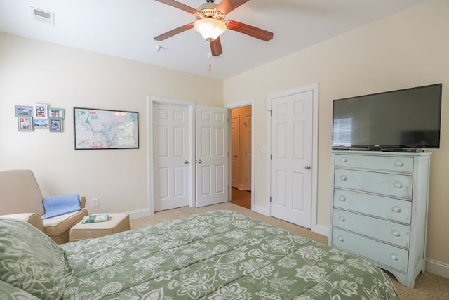 carpeted bedroom with ceiling fan and two closets