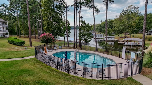 view of pool with a water view, a patio area, and a lawn