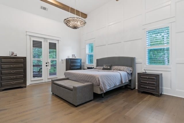 bedroom featuring access to exterior, beamed ceiling, dark hardwood / wood-style floors, and an inviting chandelier