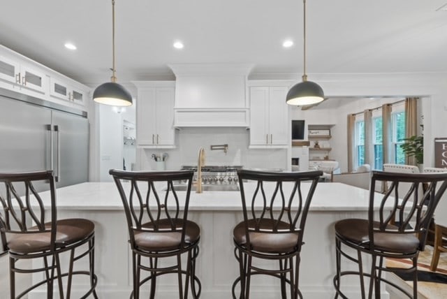 kitchen featuring stainless steel built in fridge, a breakfast bar, and hanging light fixtures