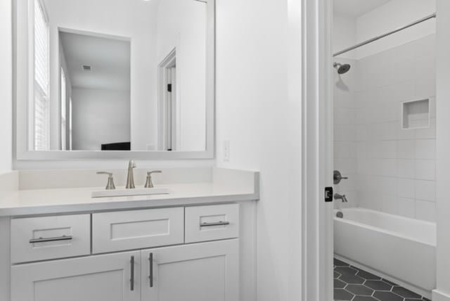 bathroom featuring tiled shower / bath combo and vanity