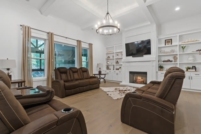 living room featuring beamed ceiling, light hardwood / wood-style floors, an inviting chandelier, and coffered ceiling