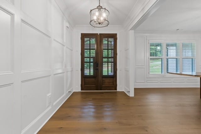 entrance foyer featuring a chandelier, french doors, dark hardwood / wood-style flooring, and ornamental molding