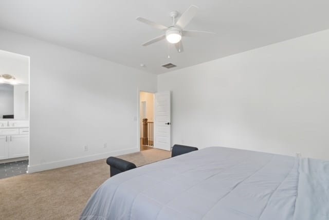 carpeted bedroom with ensuite bathroom and ceiling fan