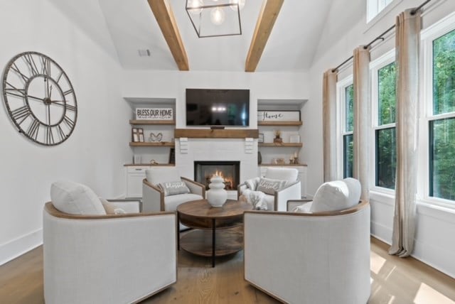 living room with vaulted ceiling with beams and light wood-type flooring