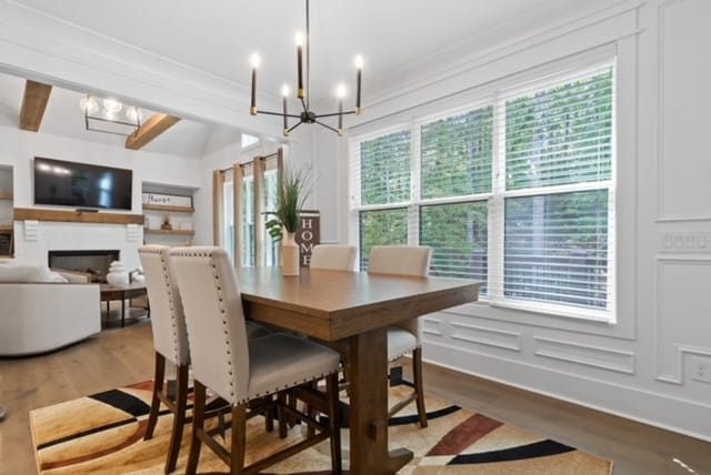 dining area with beamed ceiling, a chandelier, and hardwood / wood-style flooring