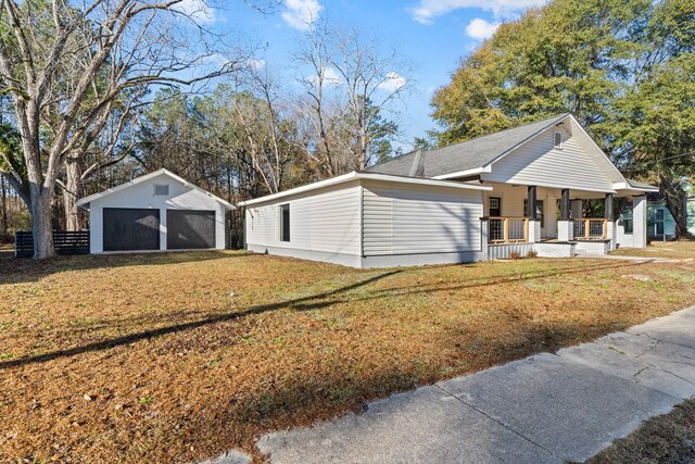 174 Main St, Toomsboro, GA 31090 - view of property exterior featuring a porch, a lawn, an outbuilding, and a garage