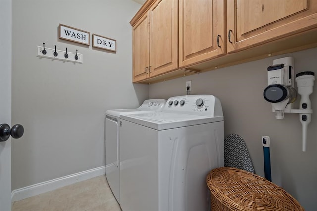 washroom with light tile patterned flooring, baseboards, separate washer and dryer, and cabinet space