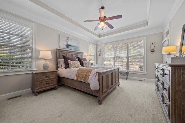 bedroom with a tray ceiling, multiple windows, light colored carpet, and crown molding