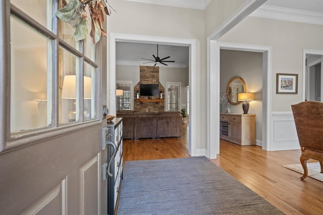 entryway with wood finished floors, ornamental molding, and ceiling fan