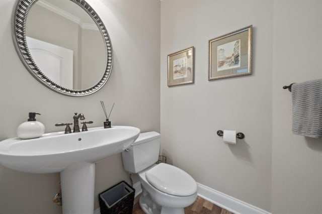 half bathroom with toilet, baseboards, and wood finished floors