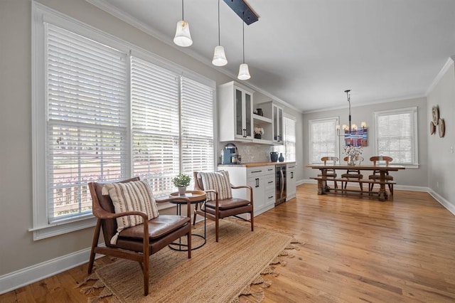 dining room with crown molding, a chandelier, light wood finished floors, beverage cooler, and baseboards