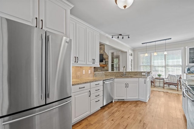kitchen featuring white cabinetry, ornamental molding, a sink, and stainless steel appliances