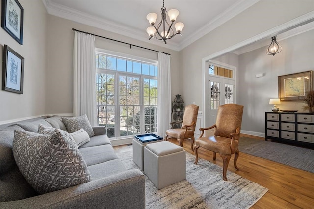 living area featuring baseboards, a notable chandelier, wood finished floors, and ornamental molding