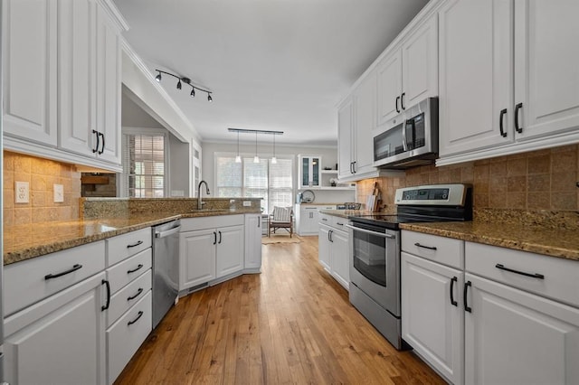 kitchen with white cabinetry, a sink, ornamental molding, and appliances with stainless steel finishes