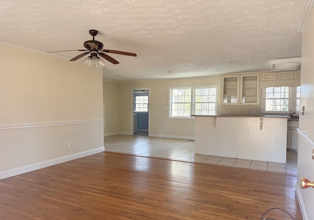 unfurnished living room featuring ceiling fan, light hardwood / wood-style flooring, sink, and a textured ceiling