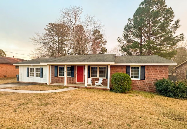 ranch-style house with covered porch and a lawn