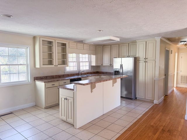 kitchen featuring sink, light tile patterned floors, a kitchen island, stainless steel appliances, and cream cabinets