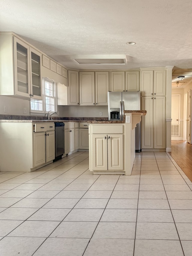 kitchen with cream cabinets, light tile patterned floors, a textured ceiling, and stainless steel refrigerator with ice dispenser