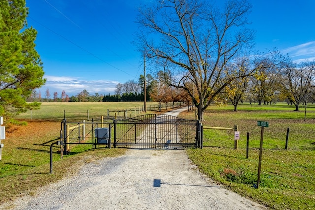 view of gate with a yard and a rural view