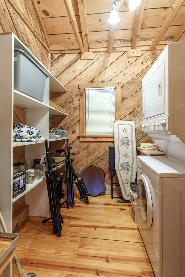 washroom featuring wood walls, light wood-type flooring, wooden ceiling, and stacked washer and clothes dryer