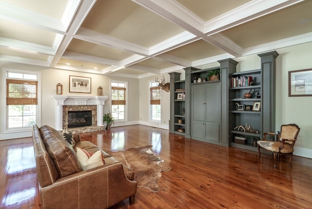 living room featuring dark hardwood / wood-style flooring, beam ceiling, a stone fireplace, and crown molding