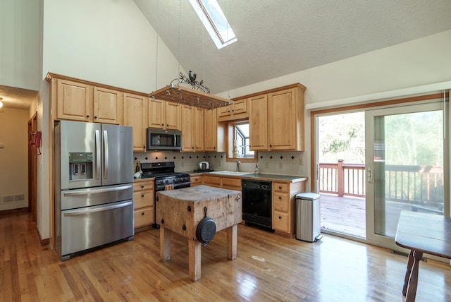 kitchen featuring a center island, backsplash, high vaulted ceiling, black appliances, and a skylight