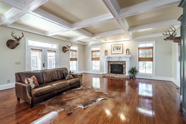 living room featuring beamed ceiling, plenty of natural light, a stone fireplace, and dark hardwood / wood-style flooring