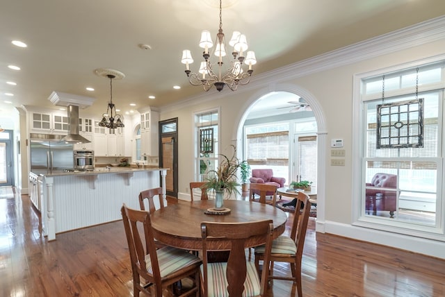 dining area with ceiling fan with notable chandelier, dark hardwood / wood-style flooring, and ornamental molding